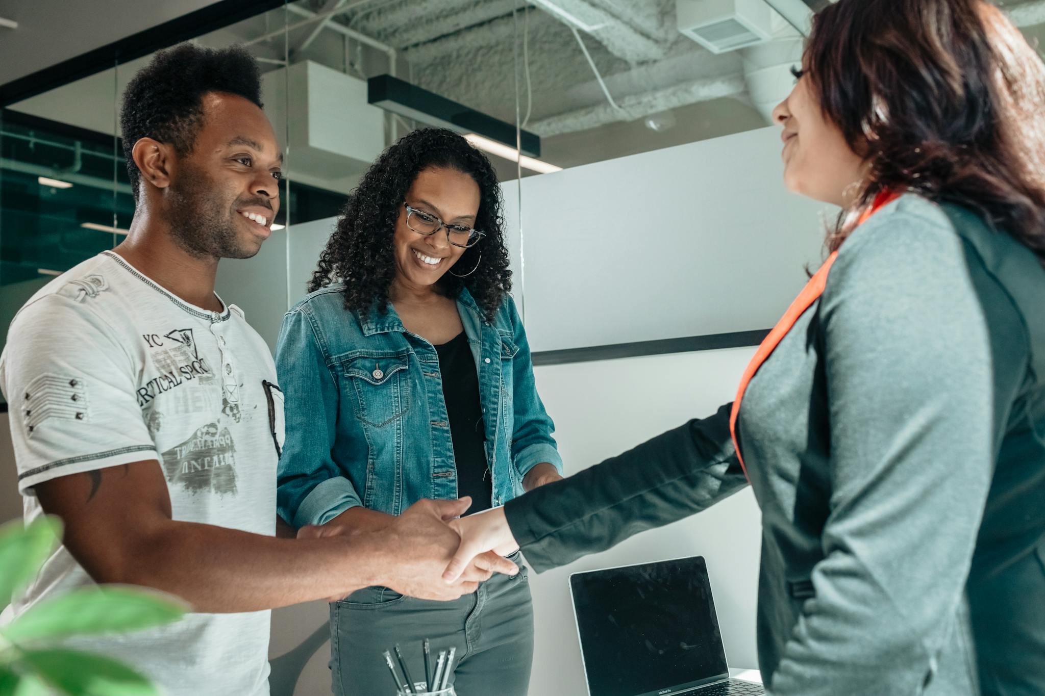Smiling Couple Shaking Hands With Advisor In